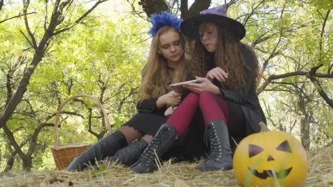 Stock Video Little Girls In Halloween Costumes Use Tablet Under Tree Animated Wallpaper - In Wallpaper