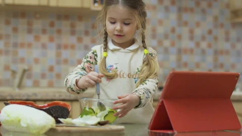 Stock Video Little Girl Stirs Salad With Spoon While Watching Video In Animated Wallpaper - In Wallpaper