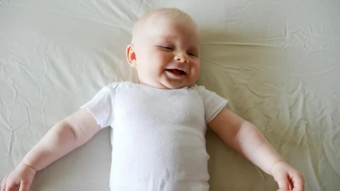 Stock Video Laughing Baby Lying On Bed In White Onesie Animated Wallpaper - In Wallpaper
