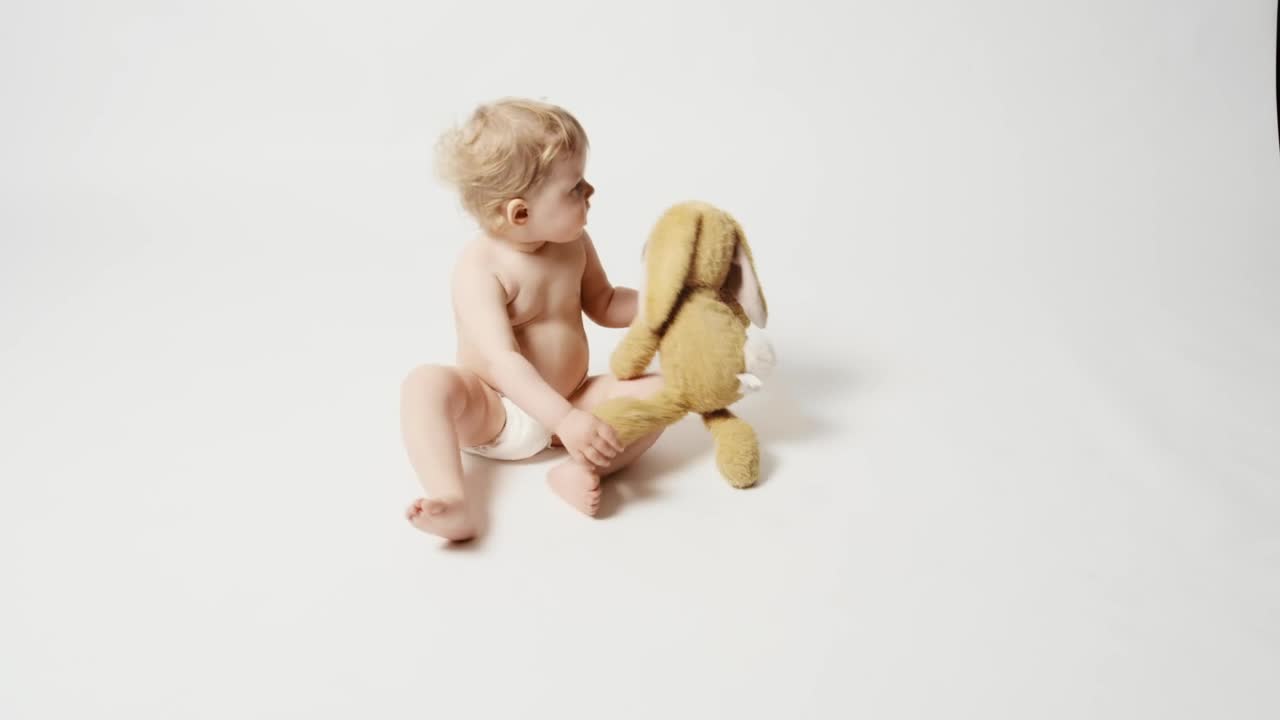 Download Stock Video Baby Girl With Plushie Sitting On A White Background Live Wallpaper For PC