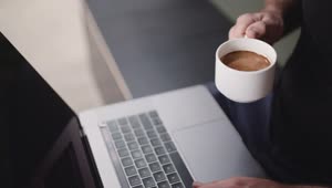Stock Video A Person Drinking Coffee While Using A Laptop Live Wallpaper For PC
