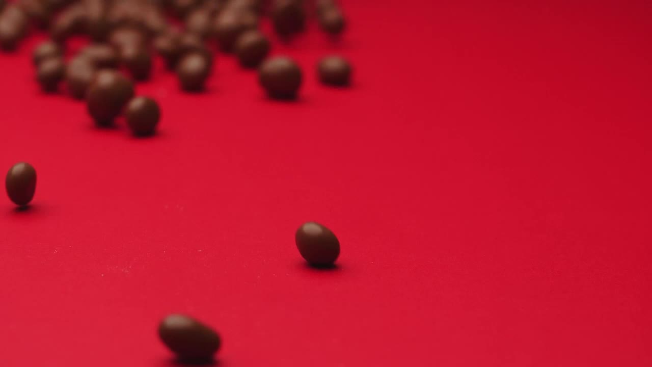 Download Video Stock Chocolate Beans Rolling On A Red Surface Live Wallpaper For PC