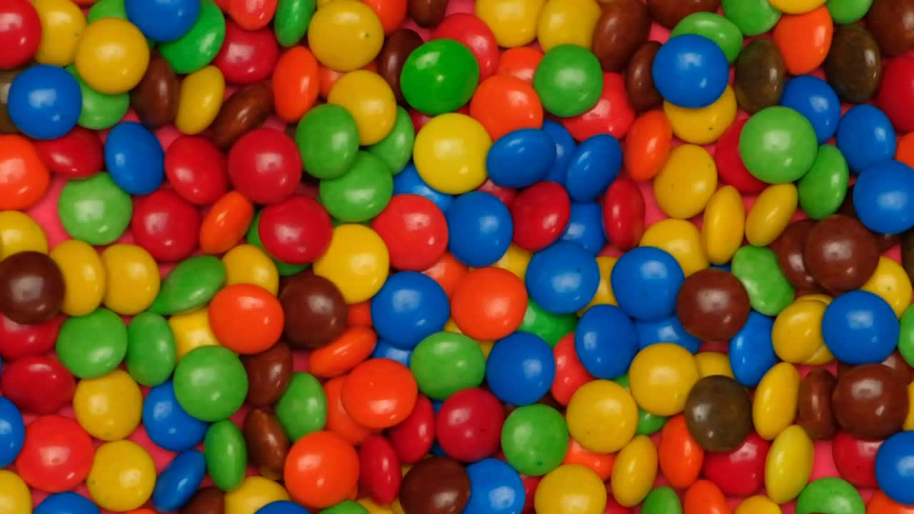 Download Stock Video Colored Chocolates Jumping On A Pink Background Live Wallpaper For PC