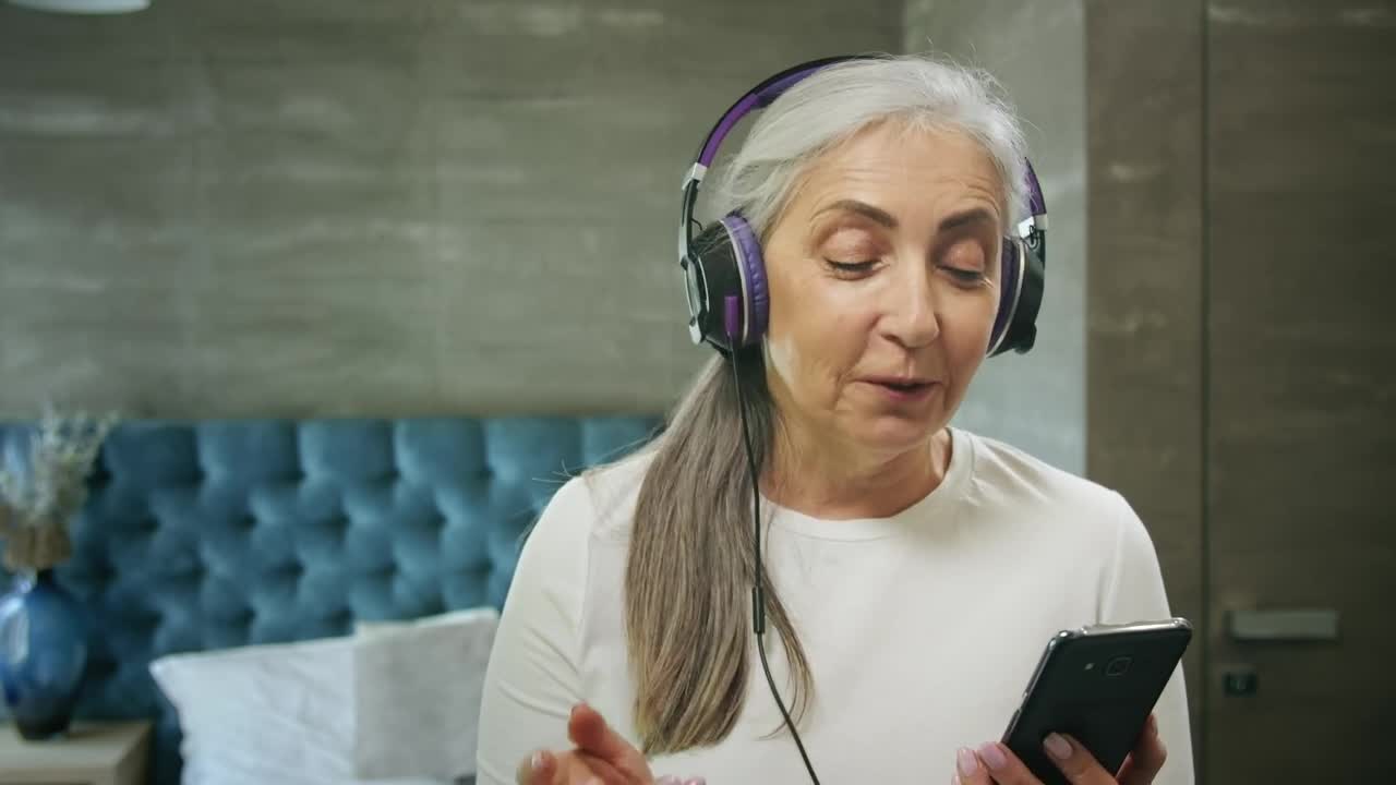 Download Stock Video Elderly Woman Enjoys Music App With Headphones Live Wallpaper For PC