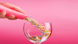Stock Video Filling A Glass Cup With Small Sweets On A Pink Live Wallpaper For PC