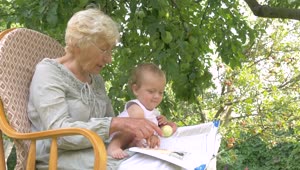 Stock Video Grandma Reads Book To Baby Under Apple Tree Live Wallpaper For PC