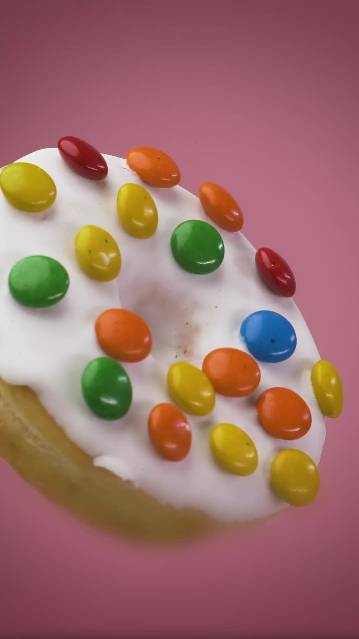 Download Stock Video Glazed Donut With Colored Chocolates On A Pink Background Live Wallpaper For PC