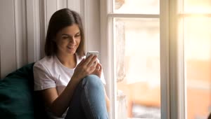 Stock Video Happy Woman Uses Mobile App Sitting In Window Animated Wallpaper