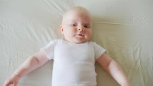 Stock Video Happy Baby Lying On White Bed In White Shirt Animated Wallpaper