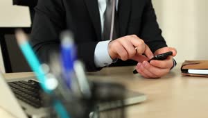 Stock Video Man In A Suit In His Office Using His Cellphone Animated Wallpaper