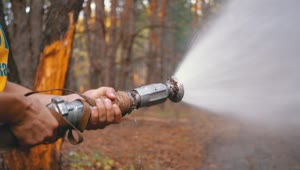 Stock Video Man Holding A Fire Hose In The Woods Animated Wallpaper