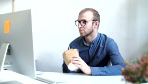 Stock Video Man Eats Take Out Food At Desk In Minimal Office Animated Wallpaper