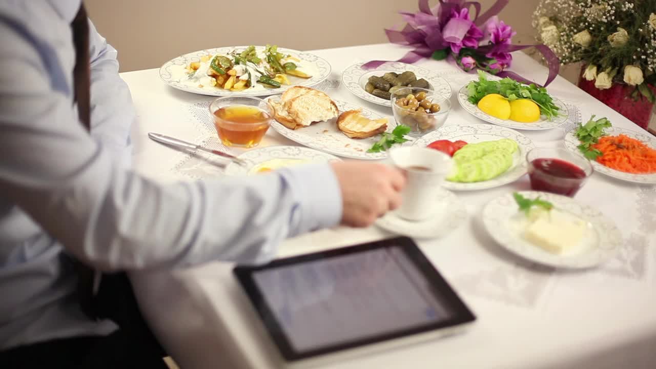 Download Stock Video Man Eating Breakfast While Working On His Tablet Animated Wallpaper