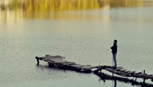 Stock Video Man Appreciating A Lake On A Worn And Broken Pier Animated Wallpaper