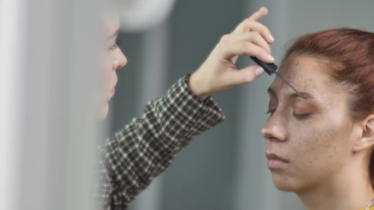 Download Stock Video Makeup Artist Putting Makeup On The Eyebrows Of A Young Animated Wallpaper