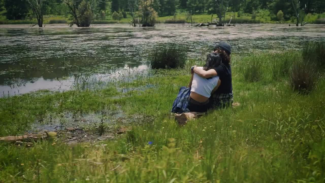 Download Stock Video Loving Couple Sitting On The Shore Of A Lake Outdoors Animated Wallpaper