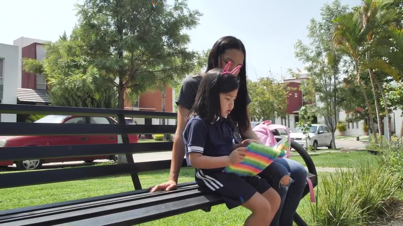 Download Stock Video Little Girl With Her Mom Reading Together In A Park Animated Wallpaper