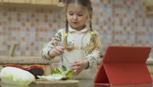 Stock Video Little Girl Stirs Salad With Spoon While Watching Video In Animated Wallpaper