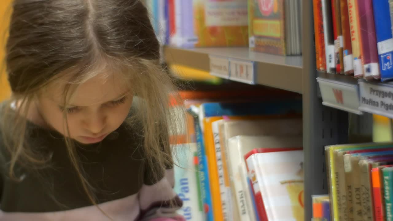 Download Stock Video Little Girl Reading A Book In A Library Animated Wallpaper