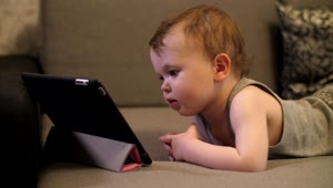 Stock Video Little Baby Looking To A Video On A Tablet Animated Wallpaper