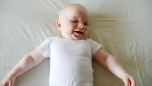 Stock Video Laughing Baby Lying On Bed In White Onesie Animated Wallpaper