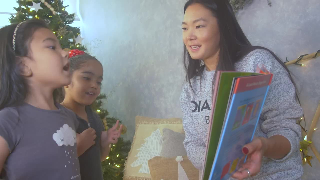 Download Stock Video Mother Reading A Book With Her Two Daughters At Christma Animated Wallpaper