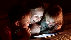 Stock Video Mother And Kids Watching Tablet On The Be Animated Wallpaper