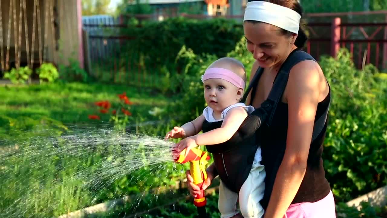 Download Stock Video Mom Watering The Garden With Her Bab Animated Wallpaper