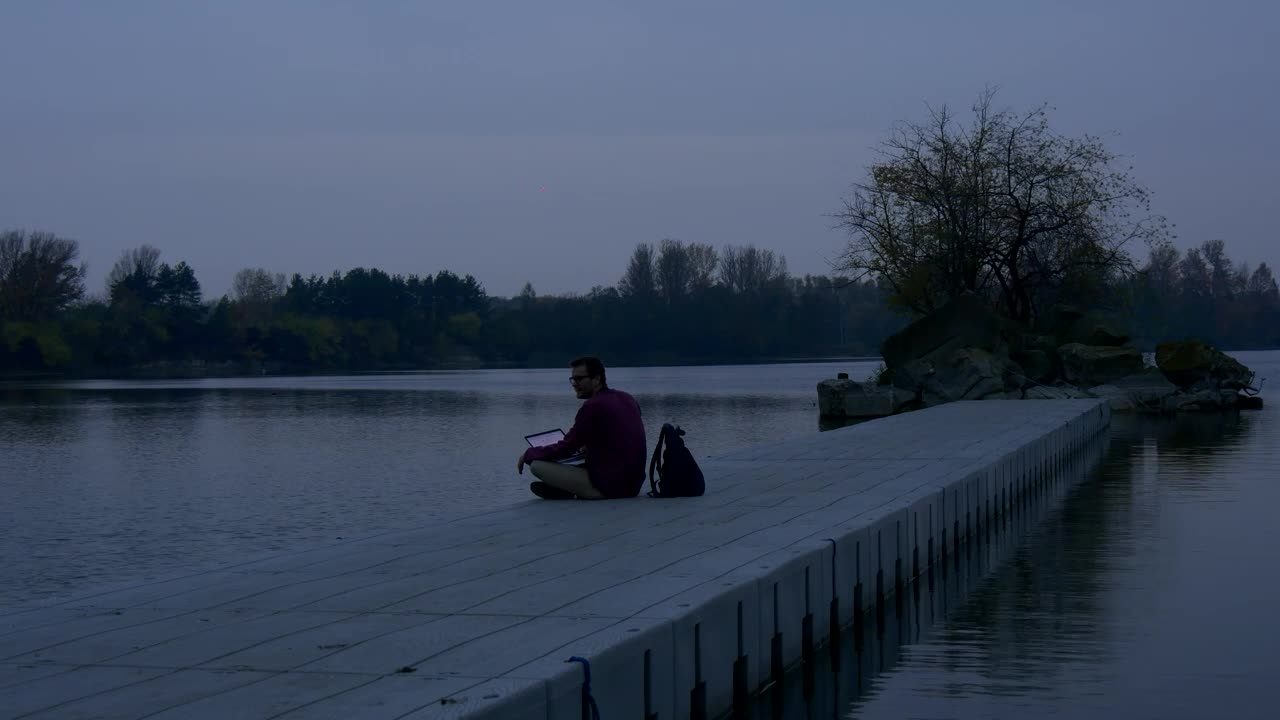 Download Stock Video Man With A Laptop On The Shore Of A Lak Animated Wallpaper