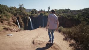 Stock Video Man Walks To A Canyon In Nature With Waterfall Animated Wallpaper