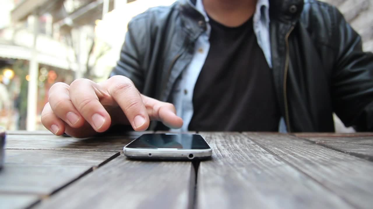 Download Stock Video Man Using A Smartphone On A Wooden Tabl Animated Wallpaper