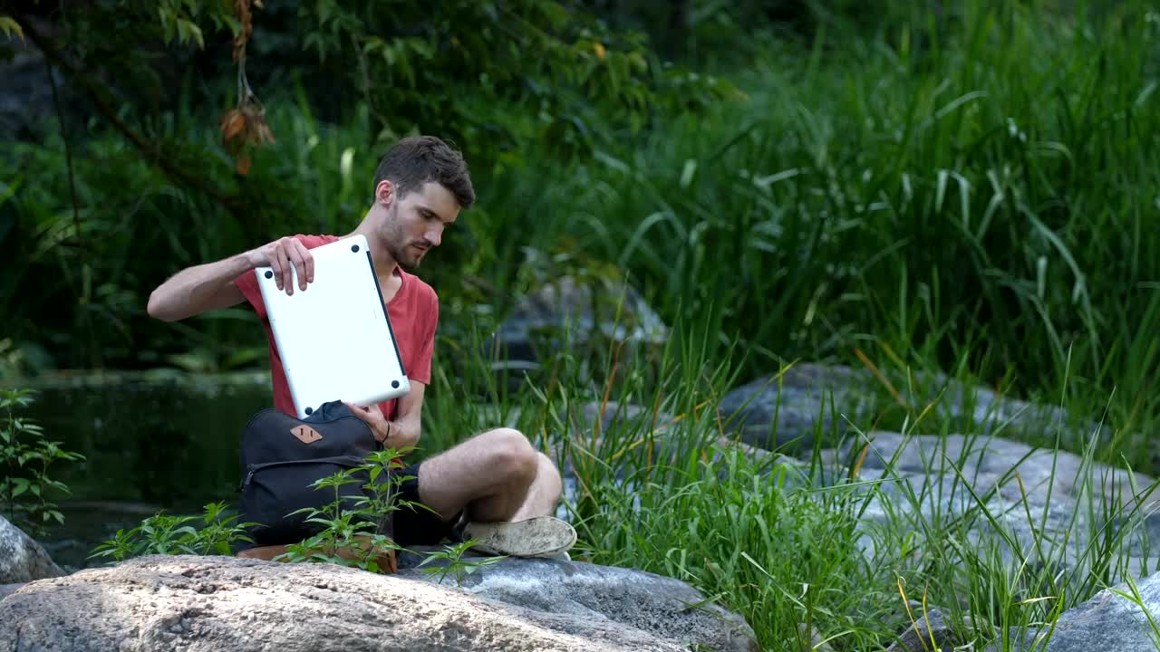 Download Stock Video Man Using A Laptop By A Strea Animated Wallpaper