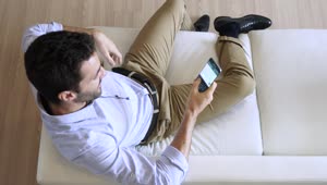 Stock Video Man Sitting On A Sofa Chatting On His Cell Phon Animated Wallpaper