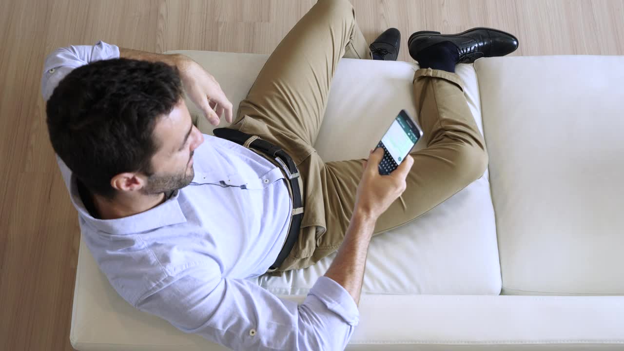Download Stock Video Man Sitting On A Sofa Chatting On His Cell Phon Animated Wallpaper