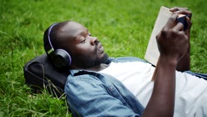 Stock Video Man Reading While Listening To Music In The Par Animated Wallpaper