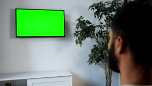 Stock Video Man Points Remote At Green Screen Tv On Wal Animated Wallpaper