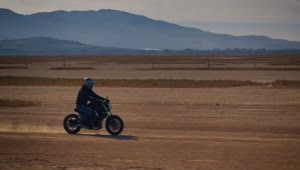 Stock Video Motorcyclist Crossing A Desert Surrounded By Mountains Live Wallpaper
