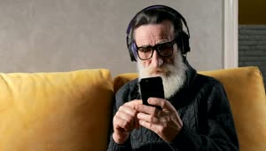 Stock Video Old Man Listens To Music With Headphones On Sofa Live Wallpaper