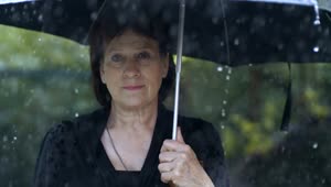 Stock Video Old Woman With Umbrella While It Rains At A Funeral Live Wallpaper