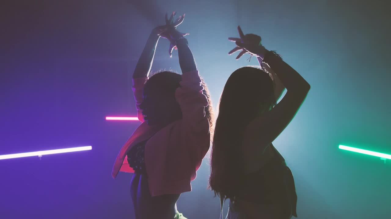 Download Stock Video Pair Of Girls Dancing Back To Back Under Colored Lights Live Wallpaper