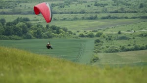 Stock Video Paraglider Floats Over Green Countryside Live Wallpaper