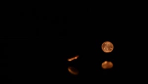Stock Video Pennies Falling On A Reflective Surface With A Dark Background Live Wallpaper