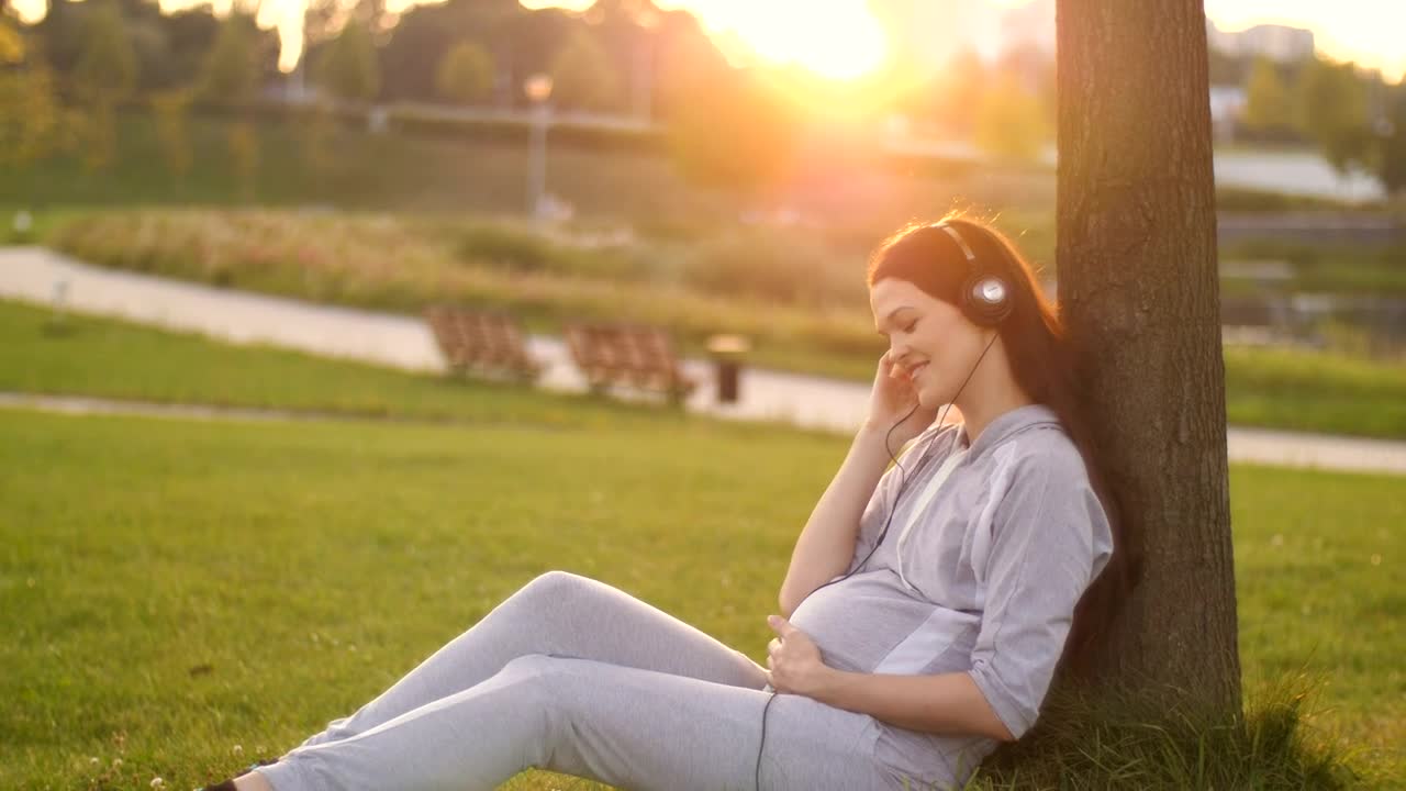Download Video Stock Pregnant Woman Listening To Music In The Park Live Wallpaper Free