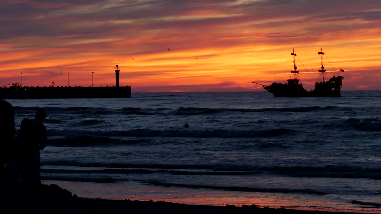 Download Free Video Stock sunset on a beach with people and a boat in Live Wallpaper
