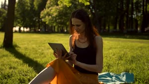 Stock Footage Woman In A Park Entertained On A Tablet Live Wallpaper Free