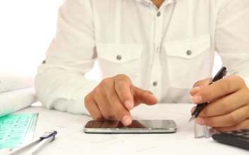 Stock Video Architect Using His Smartphone While Working For PC