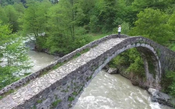 Stock Video A Woman Standing In An Old Stone Bridge Above The For PC