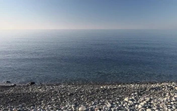Stock Video Boat Sailing In A Calm Sea Near The Rocky Beach For PC