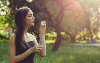 Stock Video Cute Young Woman Blowing Bubbles In The Park For PC