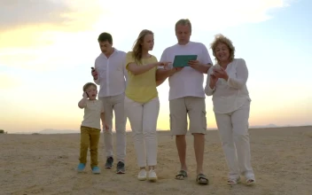 Stock Video Family Walking Along The Beach With A Tablet For PC